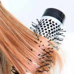 Beautiful blond woman curling her hair